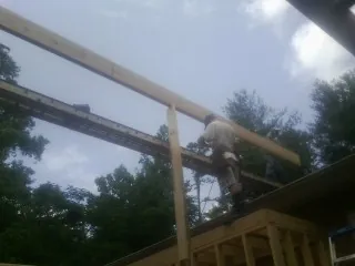 Carpenter setting a ridge beam over a new addition frame — Ice Dam Removal by Roofing Brothers in Trego