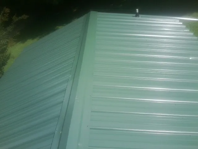 New green metal panels meeting at the ridge of a roof — Flat Roof Repair work by our crew in Trego