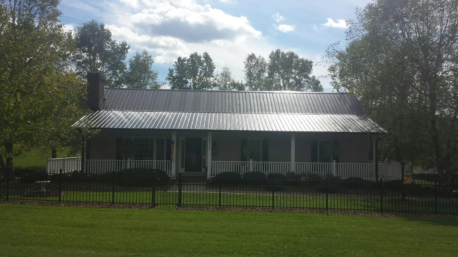 Gray metal roof on a brick ranch with a full width front porch — Gutter Guard Installation work by our crew in Trego