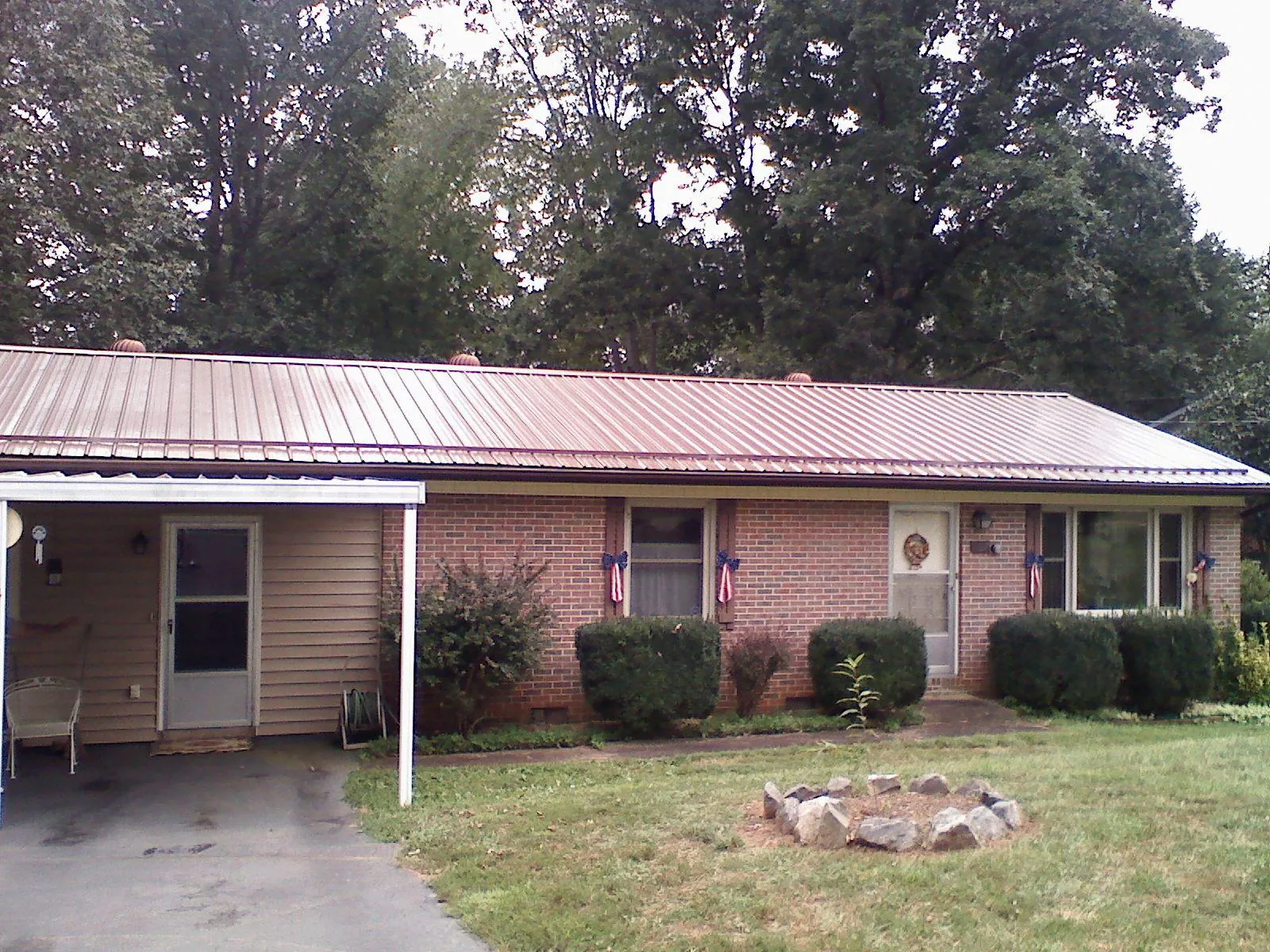 Bronze metal roof and carport on a brick ranch home — Roof Repair work by our crew in Trego