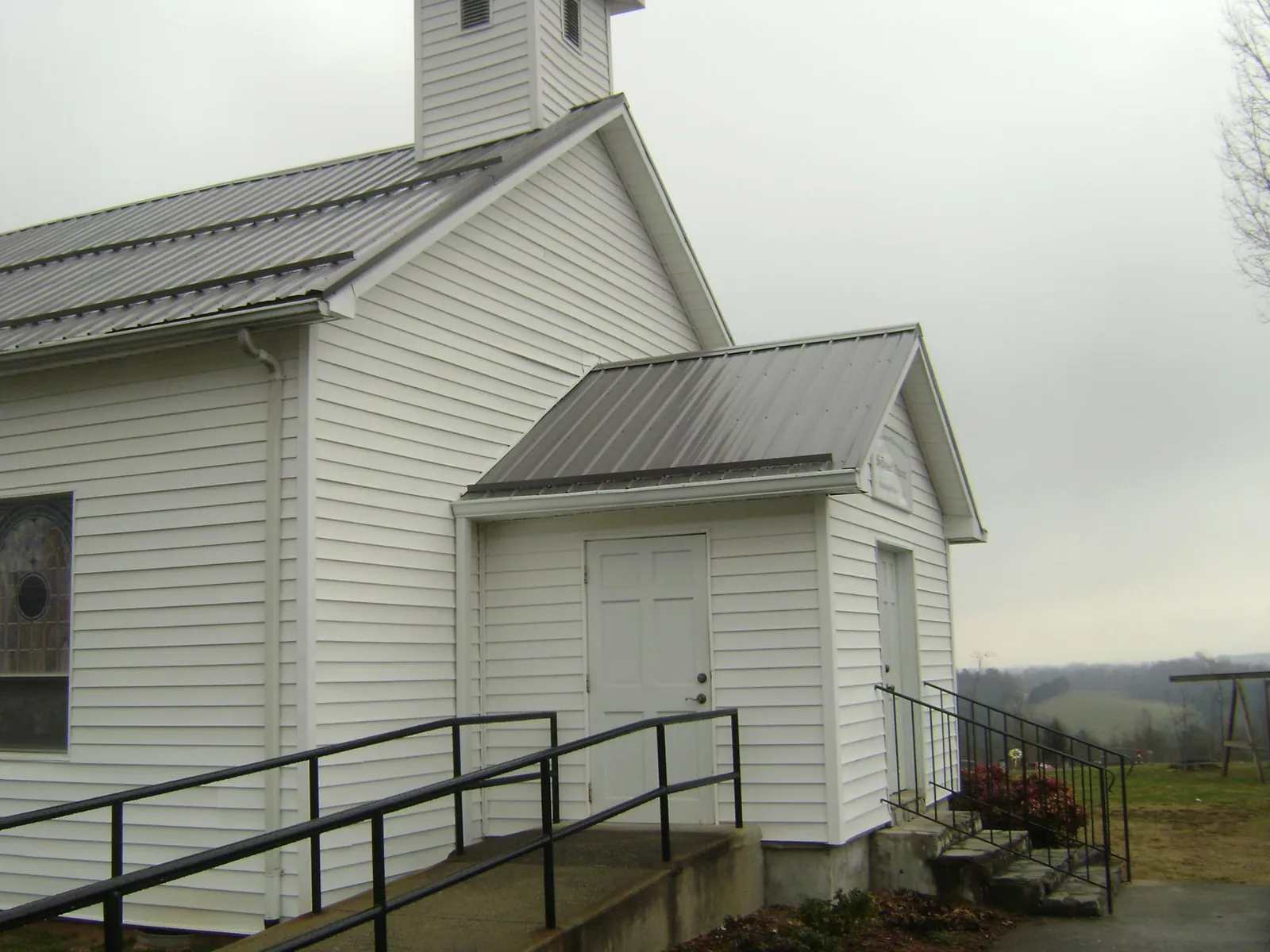 Gray metal roof on a white clapboard church with a steeple in Trego