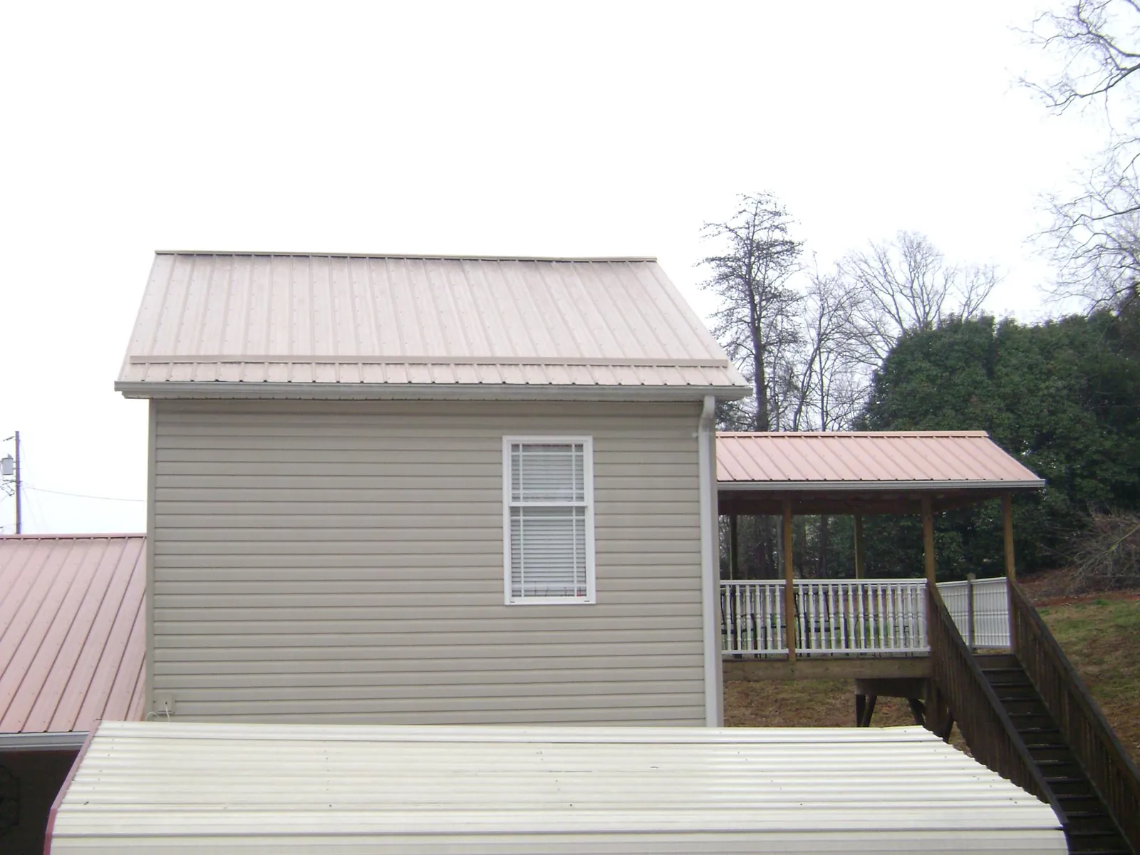 Tan metal roofs on a two story addition and attached porch, from a Roof Replacement job in Trego